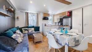 A compact living space with a sofa, dining table, and kitchenette. - Mobile Home 148 in Bois Dormant Campsite, 2 Bedrooms, 4 Guests (Saint-Jean-de-Monts)