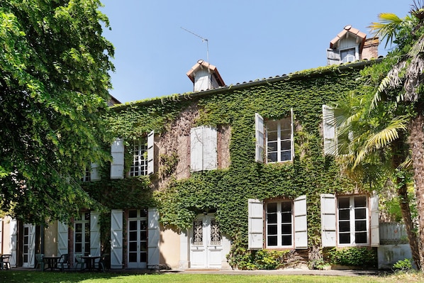A building with ivy-covered walls, white shutters, and a visible door.