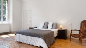 Une chambre à coucher avec un lit, une table de chevet, une chaise et une fenêtre.