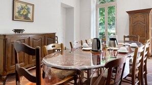 Un coin repas comprenant une table ronde, des chaises, une machine à café et un buffet.