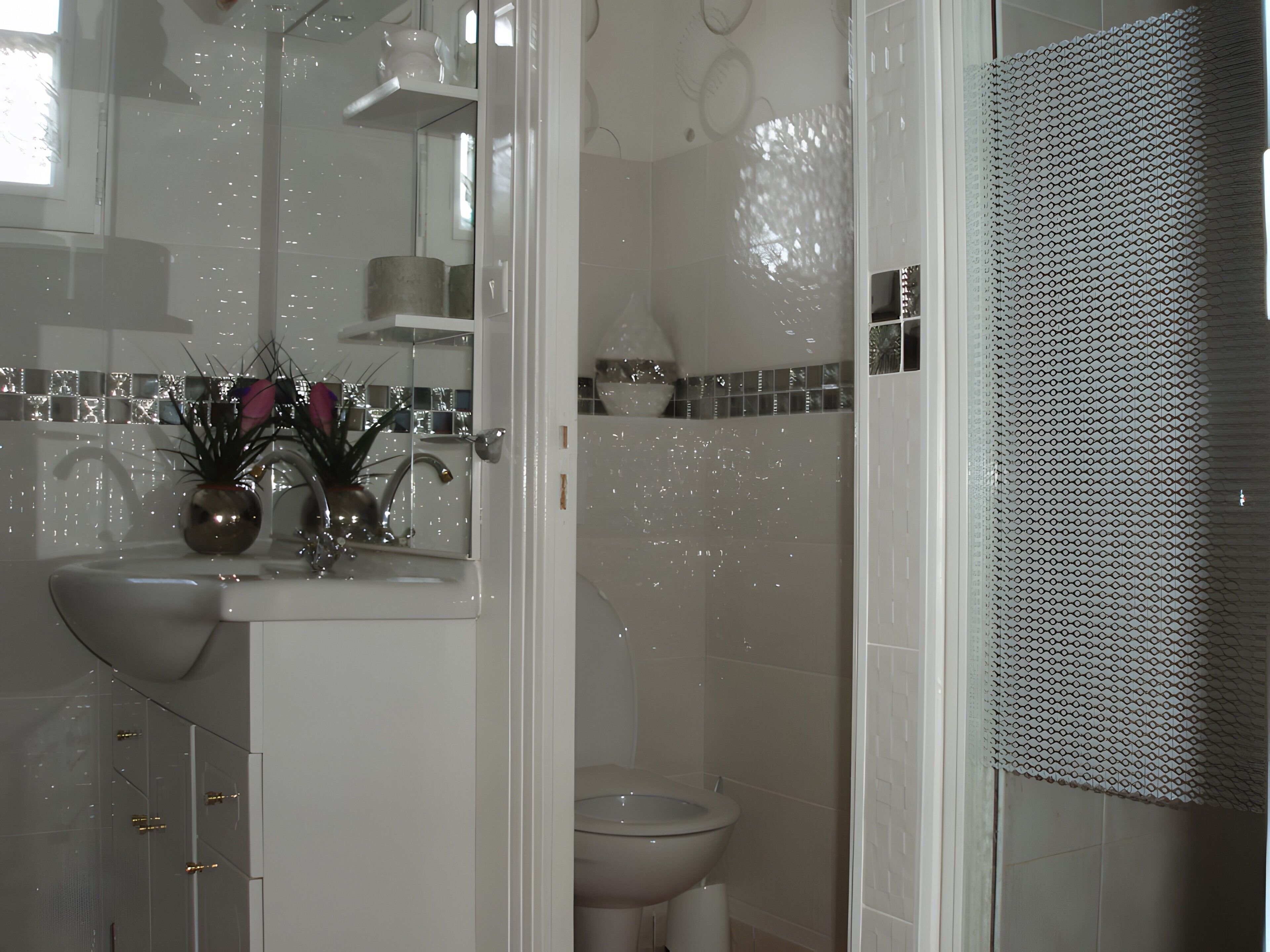 Un baño con lavamanos blanco, espejo e inodoro.