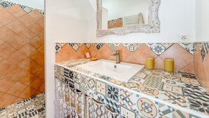 Un baño con lavamanos, espejo y azulejos estampados.