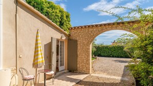 Un patio al aire libre con un arco de piedra, una mesa con sombrilla a rayas y sillas.