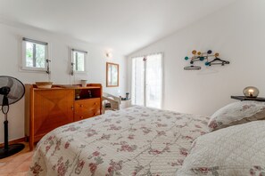 Una camera da letto con un letto, una cassettiera in legno, una ventola e un lampadario a parete.
