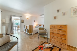 Een kamer met een bed, een stoel, een tafel met een vaas en een wand met houten dozen.