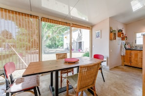 Een eetruimte met een houten tafel, rieten stoelen en uitzicht op de omgeving.