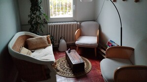 Ein Wohnzimmer mit Sofa, Sesseln, Couchtisch, Stehlampe, Heizkörper und einem großen Fenster.