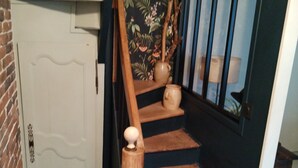 Eine Treppe mit Holzbalken, einem Geländer und einer Vase auf der Landung.