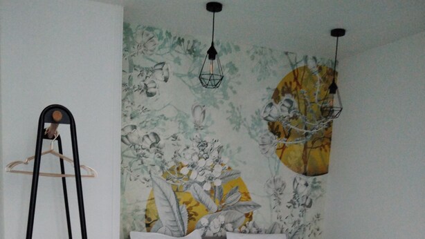 Ein Schlafzimmer mit einem Bett, einer Holzleiter und einer Wand mit floralem Wandpapier.