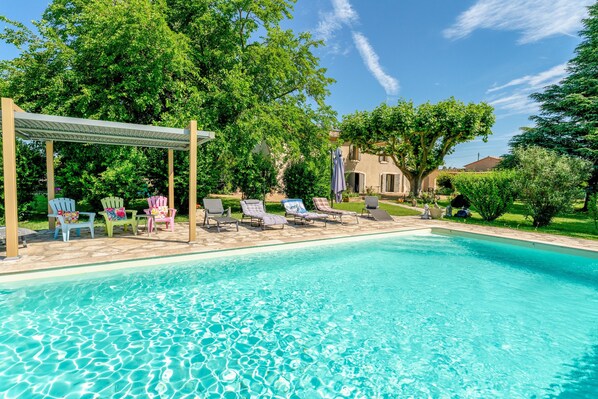 Une piscine avec des chaises longues et une pergola.