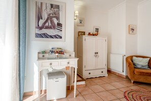 A room with a white desk, a white cabinet, a brown sofa, and a radiator.