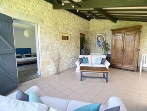 A room with a stone wall, a wooden cabinet, a white sofa with blue cushions, and a bed with a blue headboard.