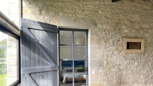 A room with a stone wall, a wooden door, a window, and a small framed picture.