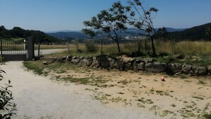 Un sendero de grava que lleva a una puerta, rodeado por un muro de piedra y césped escaso.