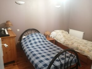 Ein kleines Schlafzimmer mit einem Bett, einem Schreibtisch inklusive Tastatur, einer Lampe und einer Heizung.
