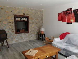 A living room with a stone wall, a wooden TV stand, a sofa, a coffee table, and a lamp.