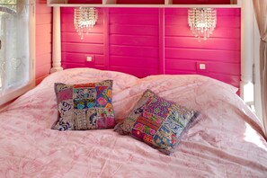 Una cama con cabecera rosa y dos almohadas decorativas.