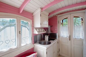 Interior rosa y blanco con zona de cocina, que incluye un lavabo y armarios.