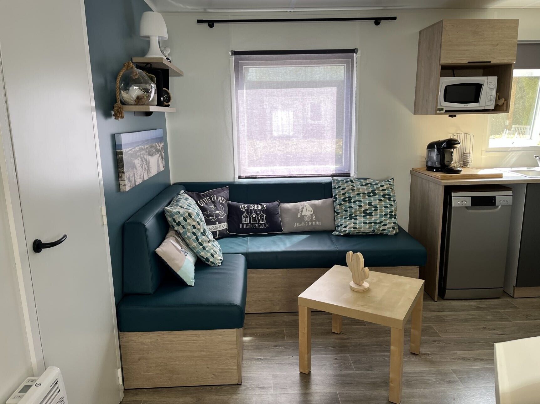A compact living space with a sofa, a small table, a microwave, and a dishwasher.