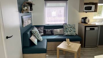 A compact living space with a sofa, a small table, a microwave, and a dishwasher.