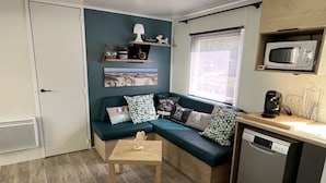 A compact living space with a sofa, a small table, a microwave, and a dishwasher. - Mobile Home 'Mobil Home Arès' in Arès, Near the Beach and Arcachon Bay (Arès)