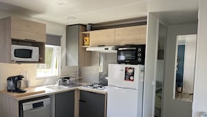 A compact kitchen with a microwave, stove, and refrigerator. - Mobile Home 'Mobil Home Arès' in Arès, Near the Beach and Arcachon Bay (Arès)