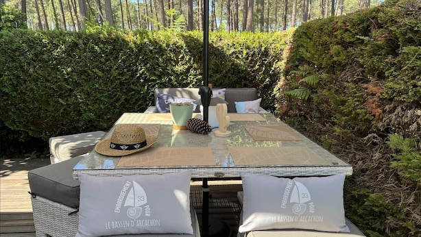 A table set outdoors with a hat, a pine cone, and a wooden sculpture. Two cushions with text are on the table. - Mobile Home 'Mobil Home Arès' in Arès, Near the Beach and Arcachon Bay (Arès)