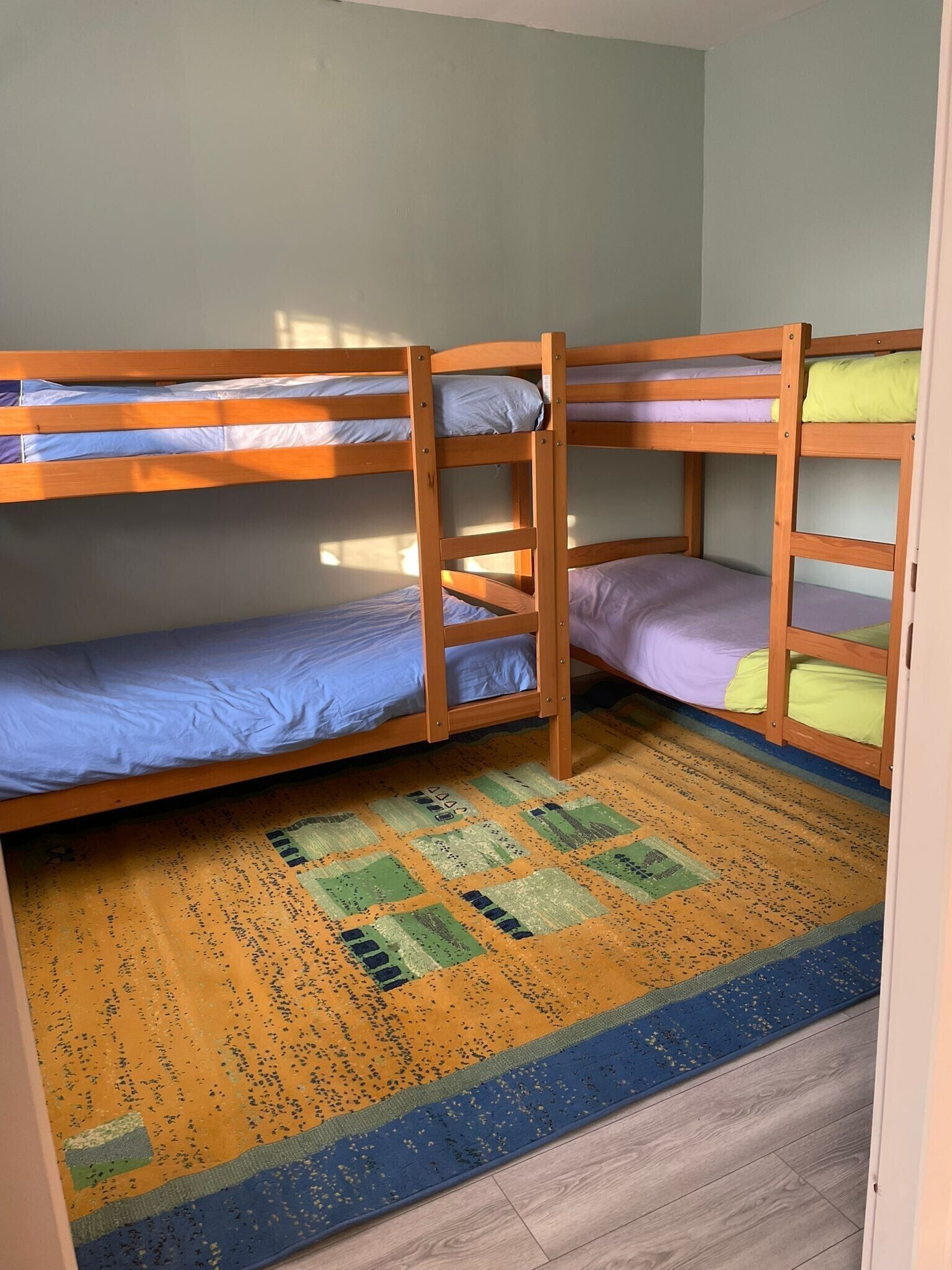 A bunk bed room with a patterned rug and wooden flooring.