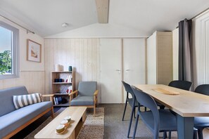 Una sala de estar moderna con un sofá, una mesa de centro, una mesa de comedor con sillas, una estantería y un armario.