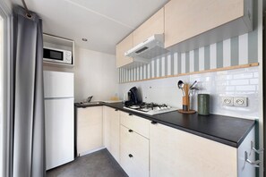 Una cocina compacta con microondas, estufa y muebles de cocina modernos.