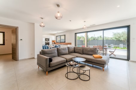 Un salon moderne avec un canapé d’angle, deux petites tables rondes et des luminaires suspendus.. Maison de vacances « Villa Moderne Avec Piscine » avec piscine privée, Wi-Fi et climatisation