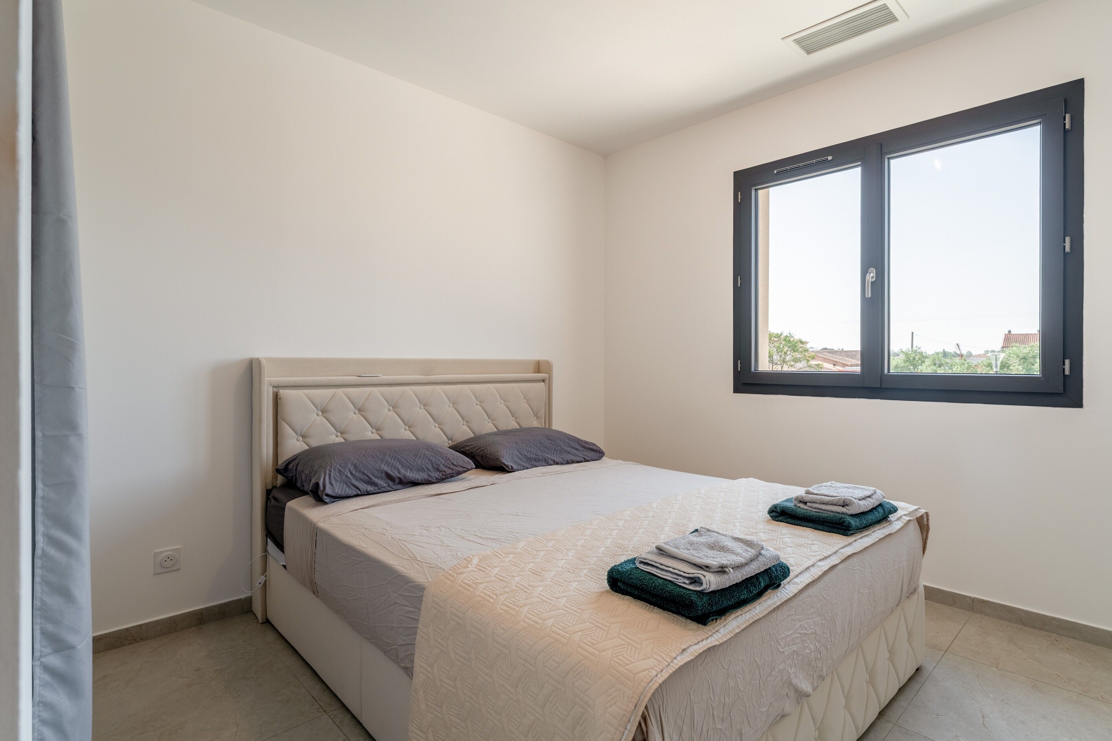 A bedroom with a bed, a window, and a view of the outside.