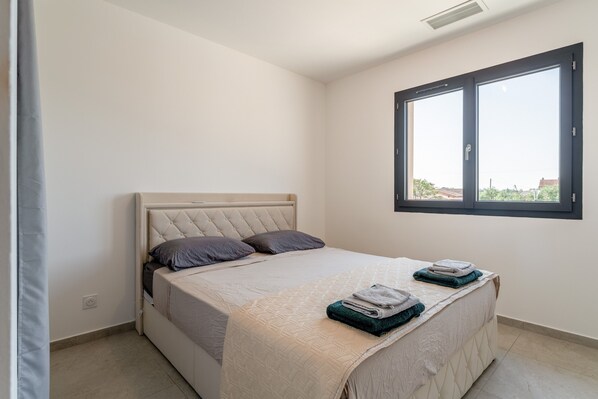 A bedroom with a bed, a window, and a view of the outside.