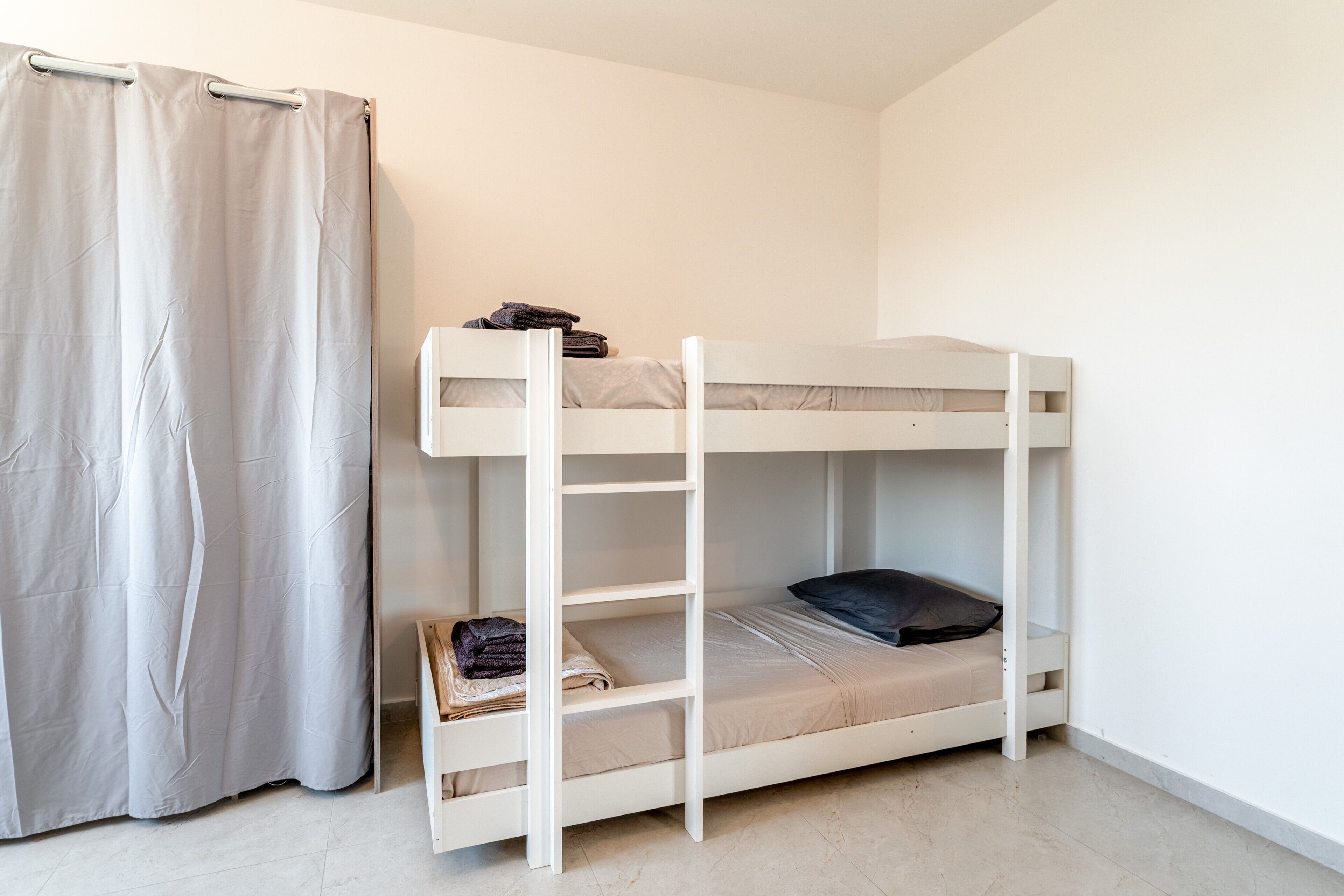 Una cama litera con escalera, una toalla doblada y un almohadón oscuro en la cama inferior.