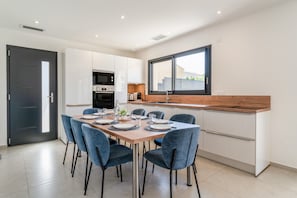 A modern kitchen with white cabinets, a wooden countertop, and a large window.