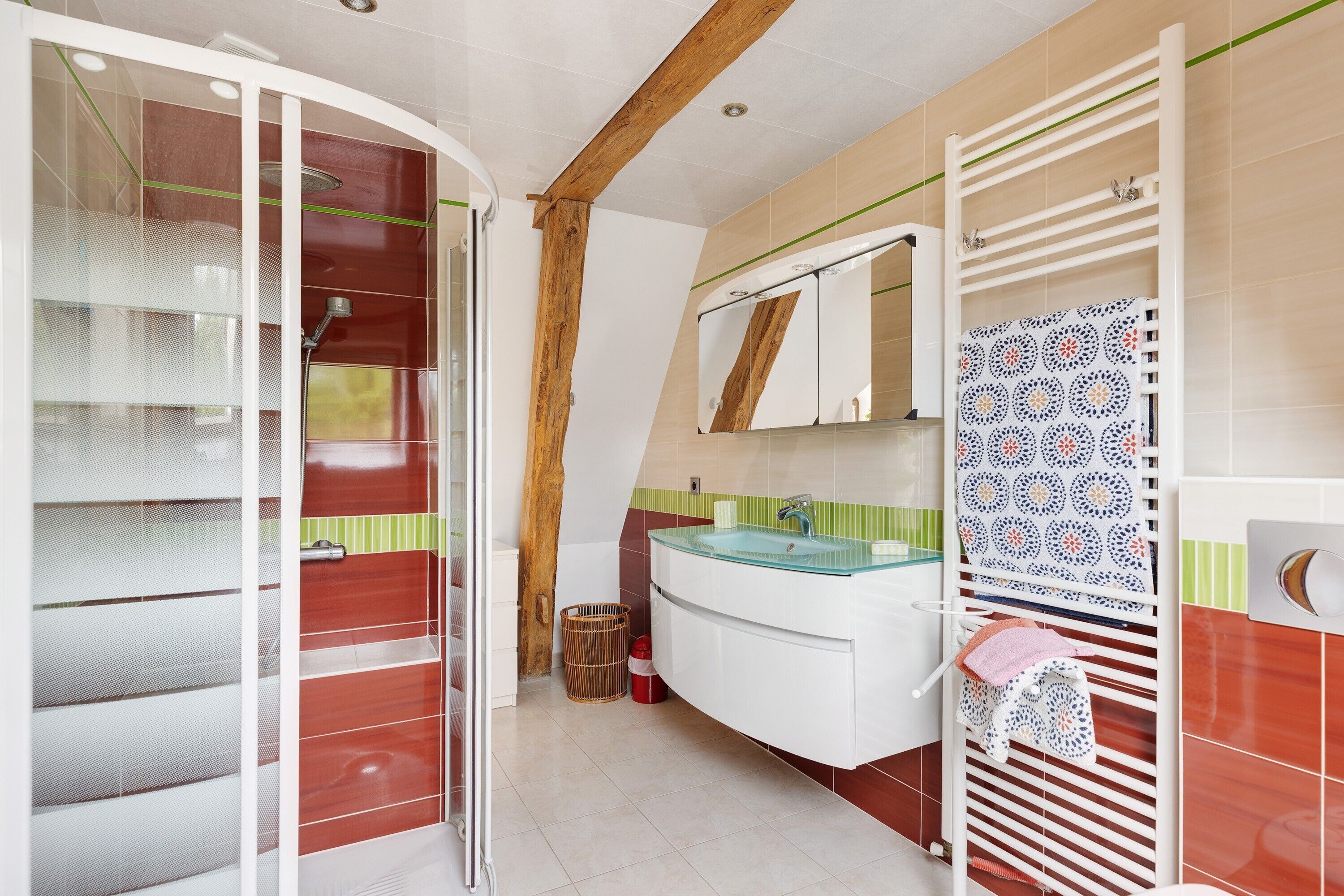 A modern bathroom with a glass shower enclosure, a white sink, and a patterned towel rack.