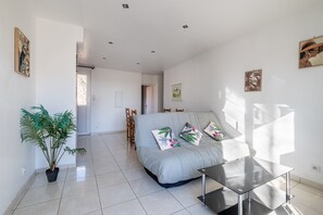 A modern living room with a sofa, a coffee table, a potted plant, and artwork on the walls. - Courtille sur Mer – Sea View and Tranquility in Fréjus (Fréjus)
