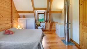 Une chambre à coucher comprenant un lit, une chaise, un bureau, une armoire et une grande cheminée.