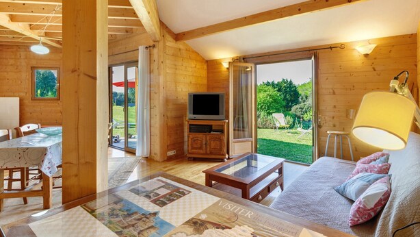 Un intérieur en bois avec un canapé, un téléviseur et une table sur laquelle est posée une carte.