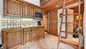 Una cocina con armarios de madera, un microondas y una escalera.