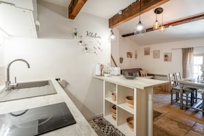 Une cuisine moderne Ă©quipĂ©e dâune cuisiniĂšre intĂ©grĂ©e, dâun Ă©vier et dâun coin repas avec une table et des chaises.