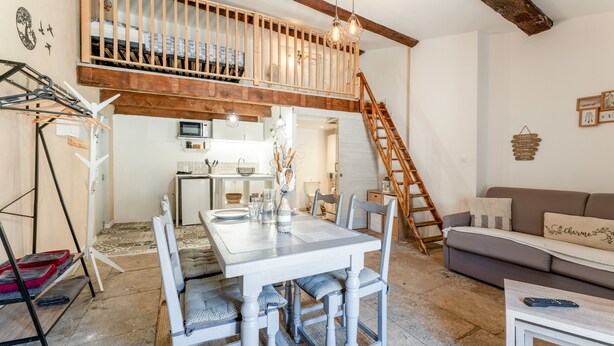 Ein Loft-Wohnraum mit Essbereich, Küche und einer Treppe, die zu einer Erkerwohnung führt.