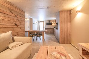 Un intérieur moderne avec un mur en bois, un canapé, une table à manger avec des chaises et un coin cuisine.