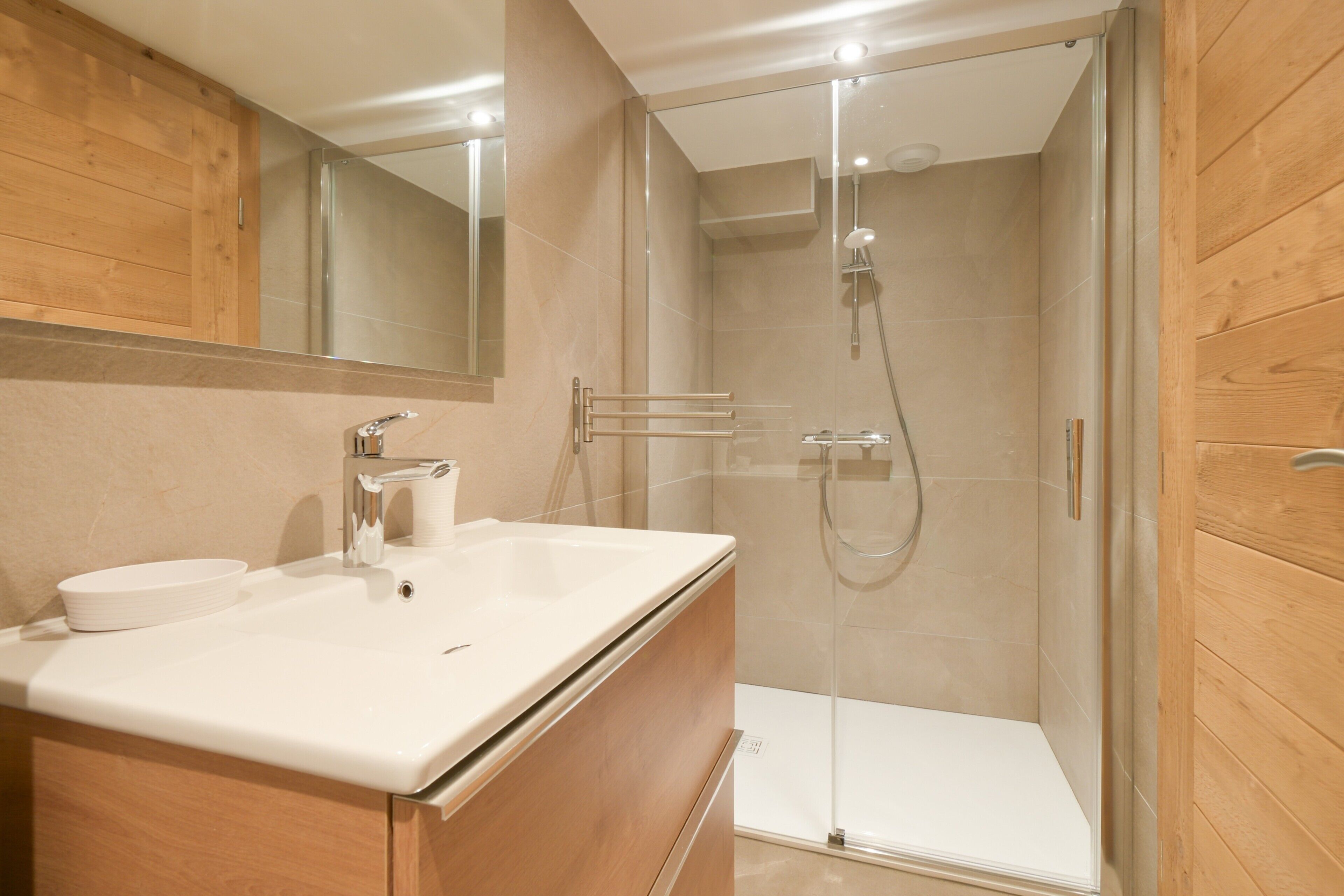 A modern bathroom with a white sink, mirror, and shower.