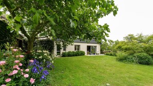 Una casa con un césped cuidado, un árbol grande y una variedad de flores.