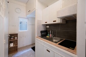 A kitchen with white cabinets, a black sink, and a window.