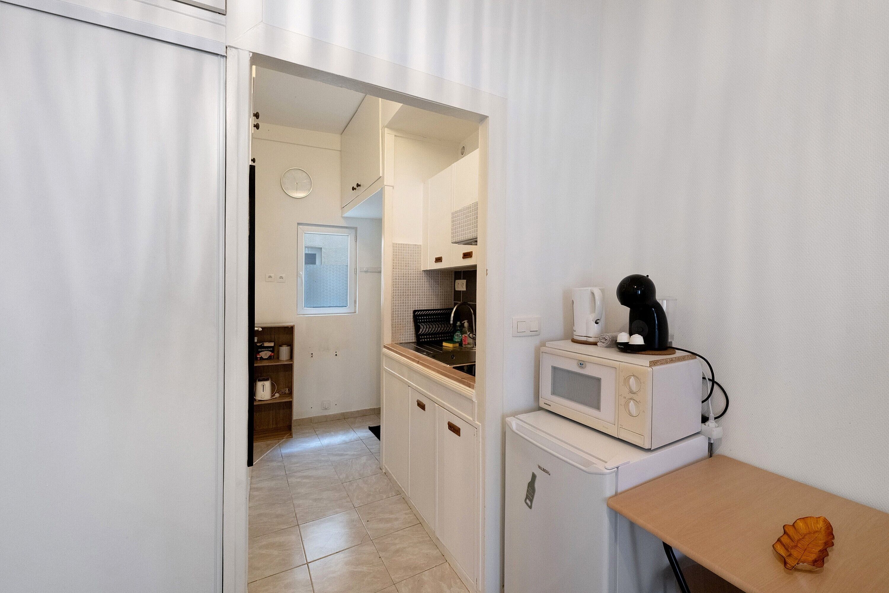 Una cocina compacta con microondas, tostadora y cafetera sobre una encimera.