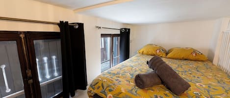A bedroom with a bed, curtains, a window, and a view of the outside.
