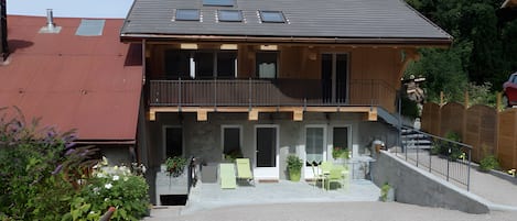 A two-story house with a balcony, a front porch, and a gravel driveway.