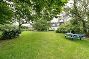 A grassy backyard with a picnic table and a house in the background. - Bed and Breakfast 'Chambres D'hôtes De Kersehen Bleue' with Shared Garden, Balcony and Wi-Fi (Plouider)